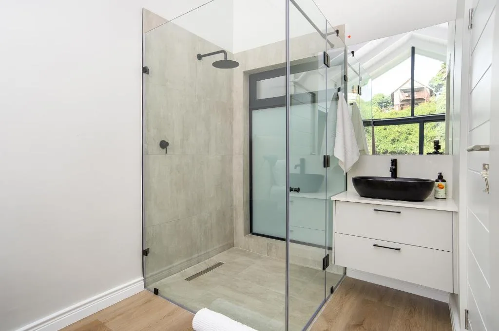 Modern bathroom with walk-in shower, black vanity sink, and natural light
