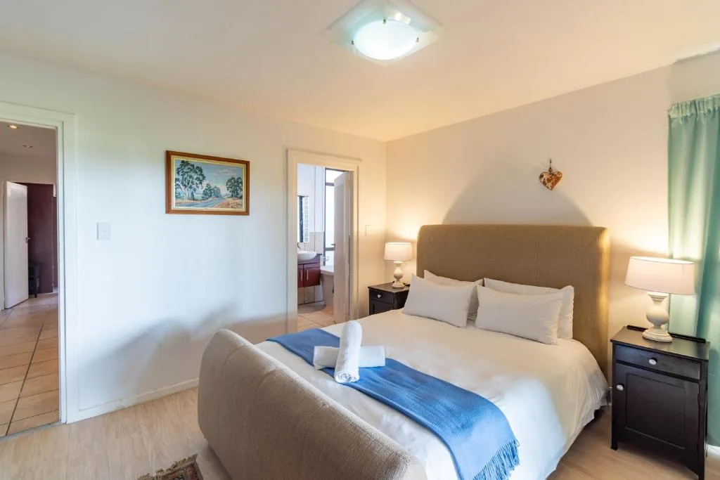 Spacious bedroom with queen bed, neutral headboard, and side lamps