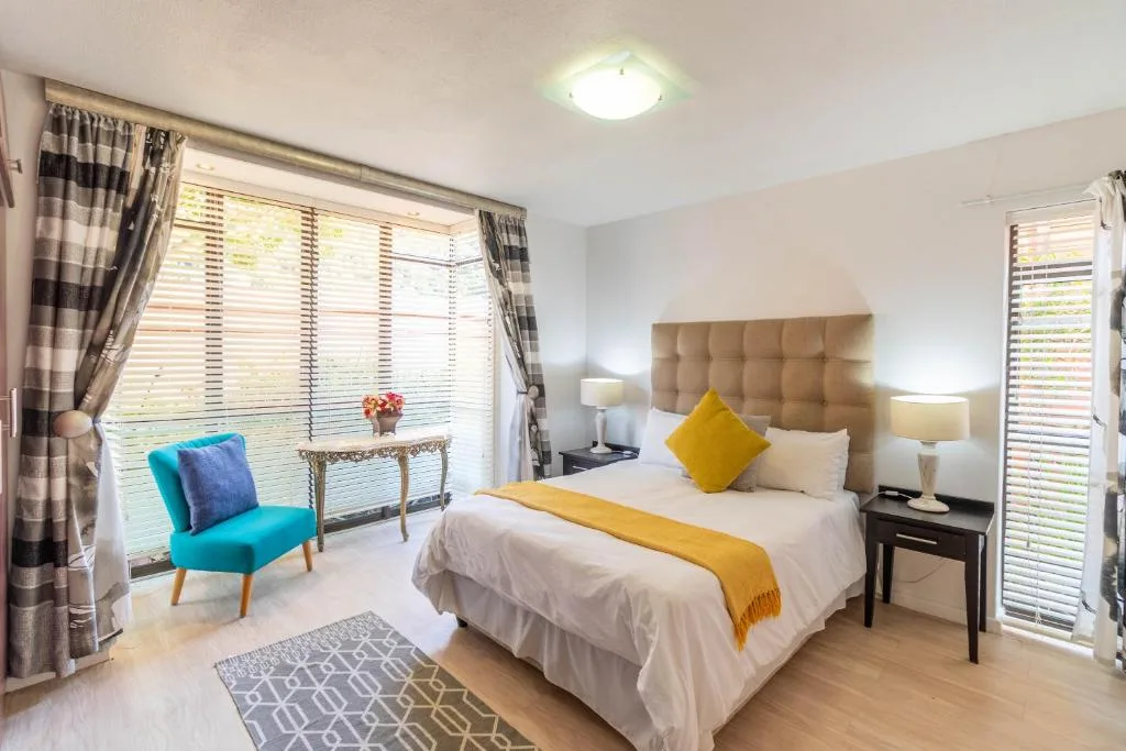 Bright bedroom with queen bed, beige headboard, yellow accents, turquoise chair