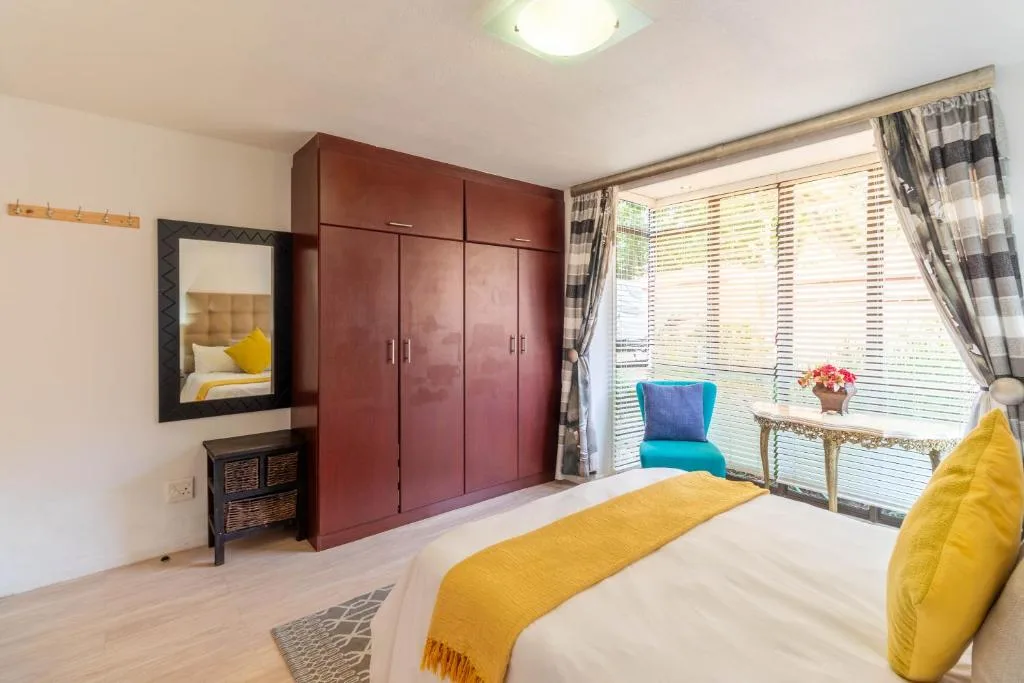 Bright bedroom with yellow accents, burgundy wardrobes, and garden views