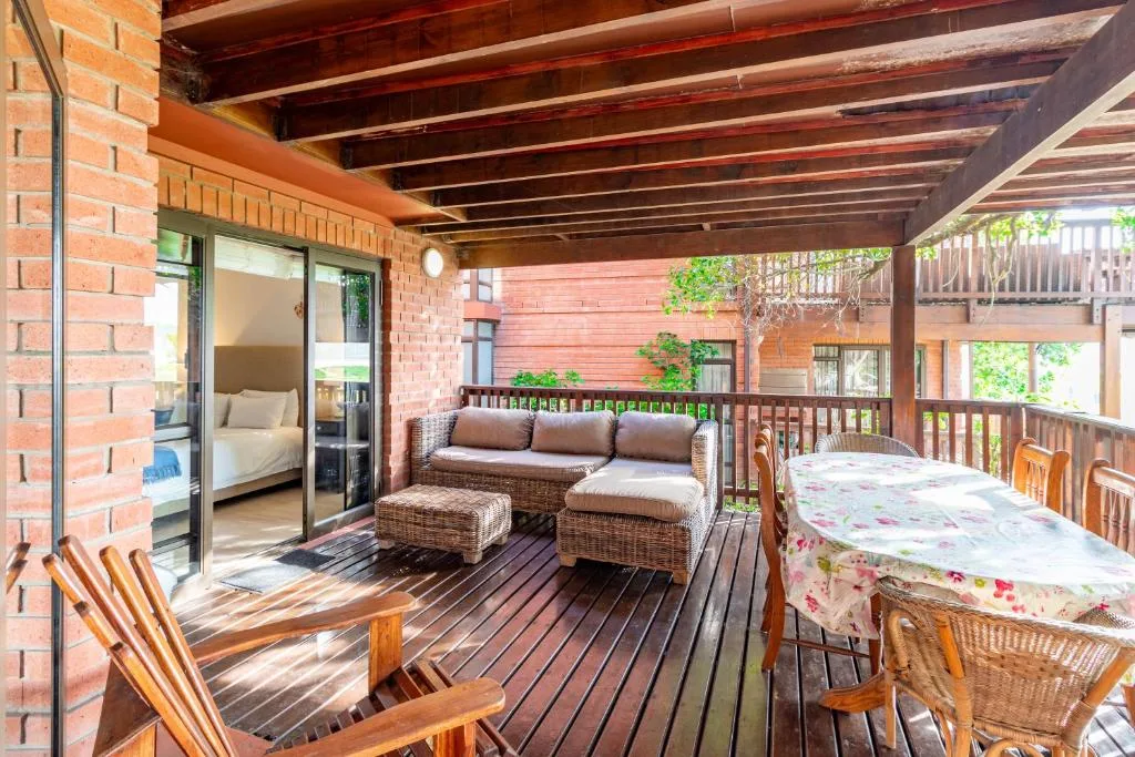 Spacious wooden deck with wicker seating, lounge chairs, and table