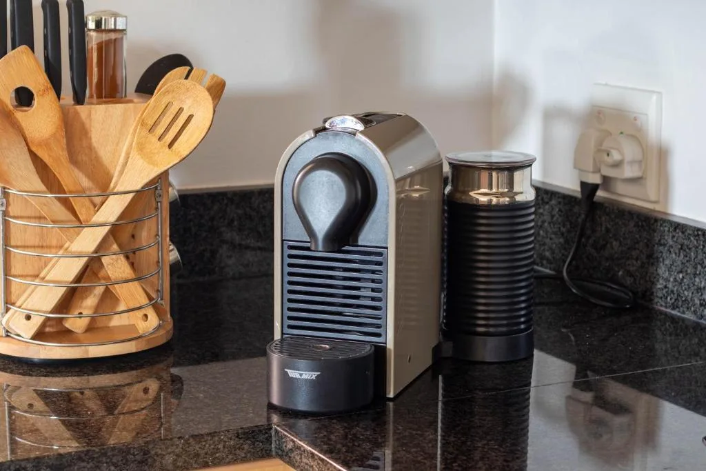 Kitchen countertop with coffee maker, milk frother, and wooden utensils holder