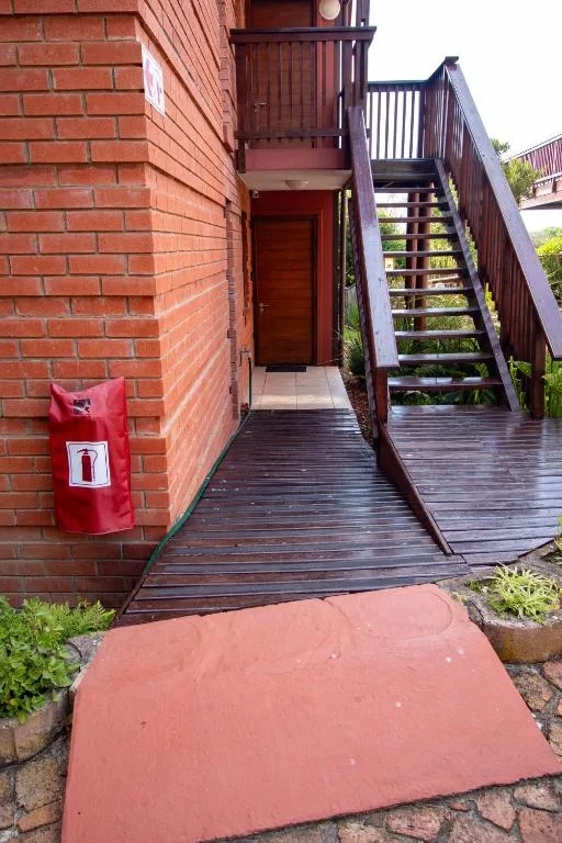 Red brick building entrance with wooden deck stairs and railings