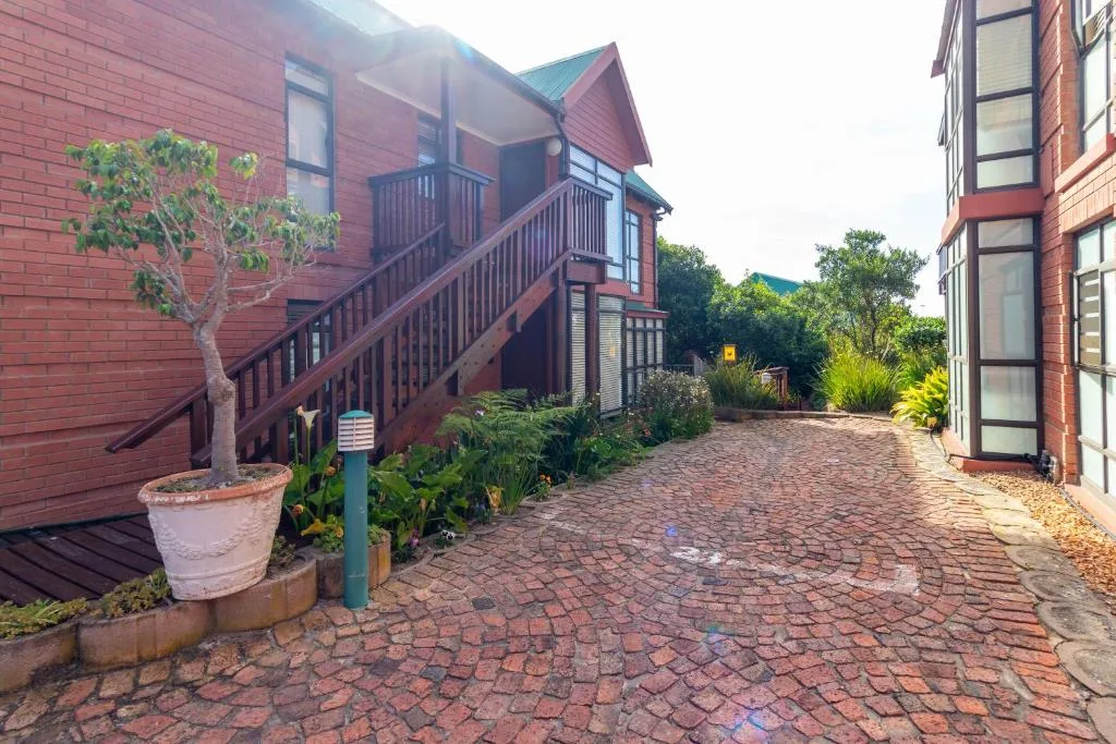 Red brick building with wooden deck stairs and potted plants in courtyard