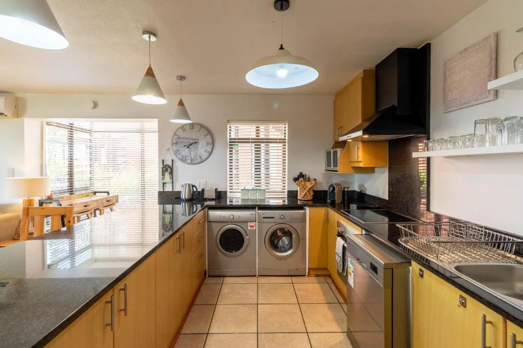 Modern kitchen with golden cabinetry, black countertops, and stainless steel appliances