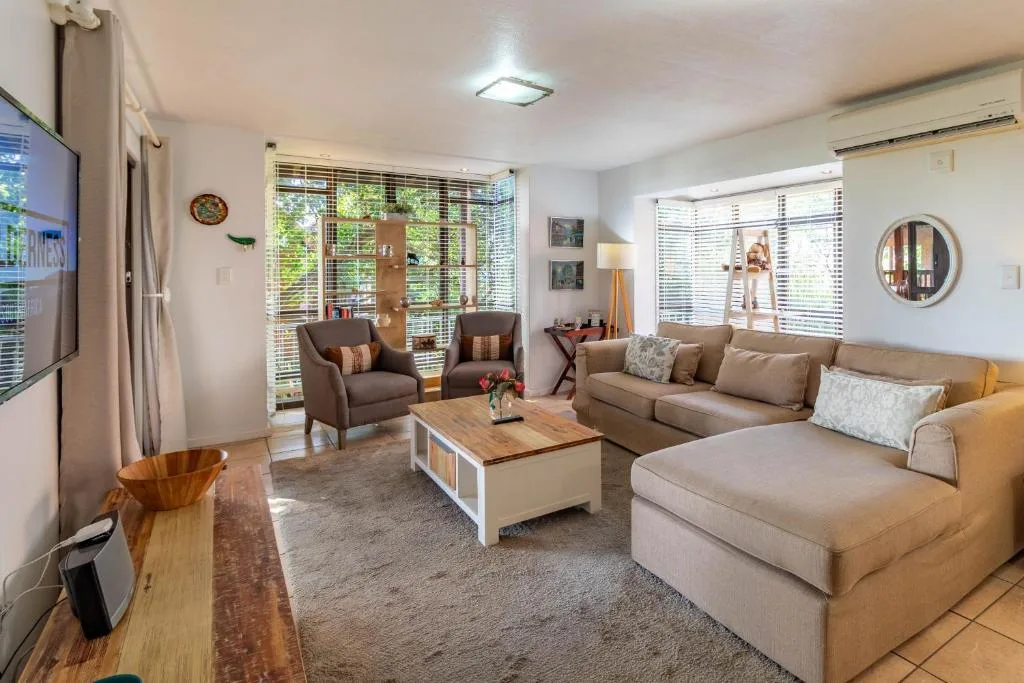 Spacious living room with beige sofas, armchairs, and wooden coffee table