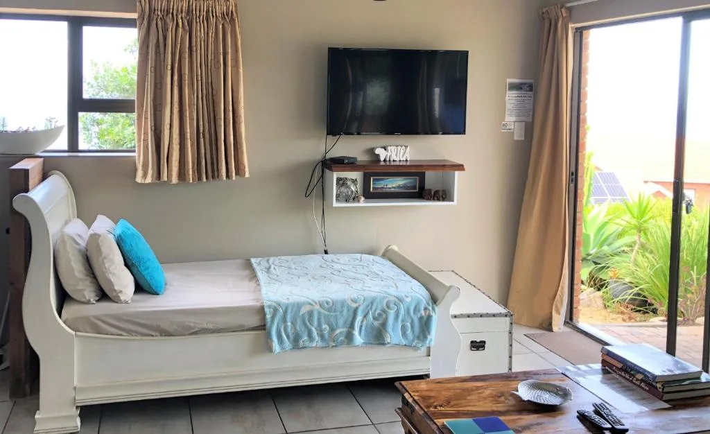 Bedroom with white sleigh bed, mounted TV, and garden view doors