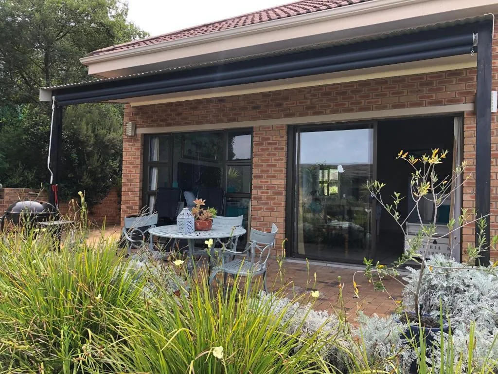 Shaded patio with dining table, chairs, and surrounding garden landscaping