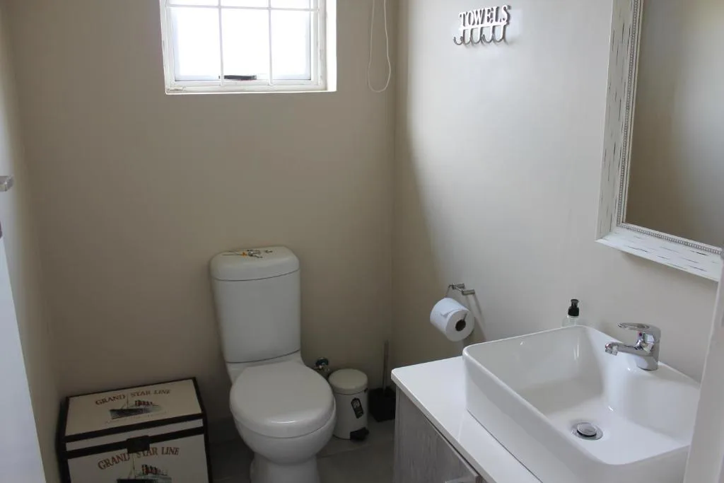 Clean bathroom with toilet, double sink vanity, and window for natural light