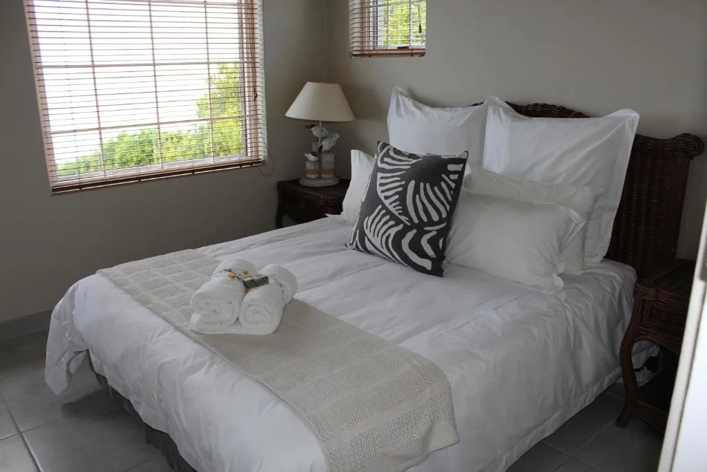 Spacious bedroom with queen bed, crisp white linens, dark wood headboard