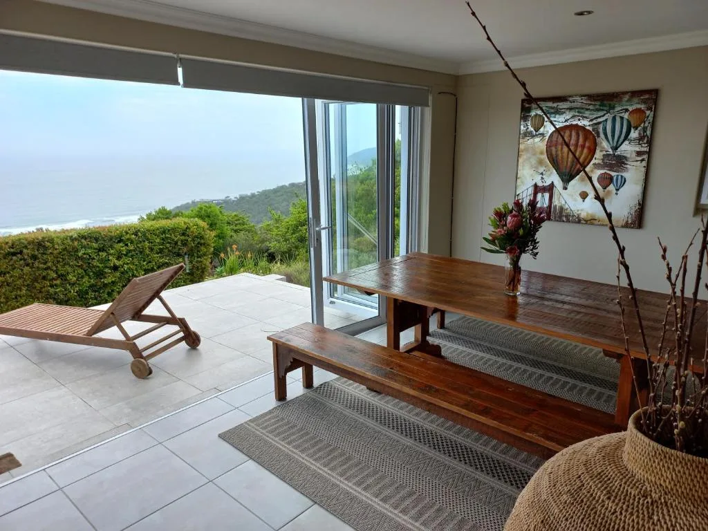 Spacious seaside deck with wooden dining table and coastal mountain views