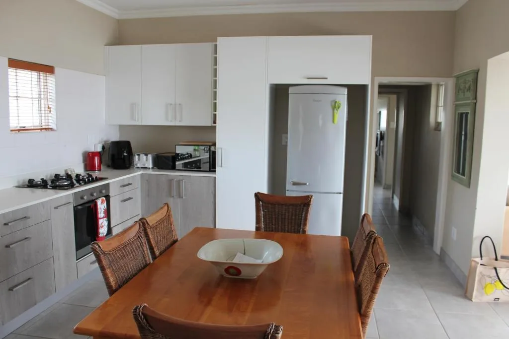Open-plan kitchen with white cabinetry, stove, refrigerator, and dining table