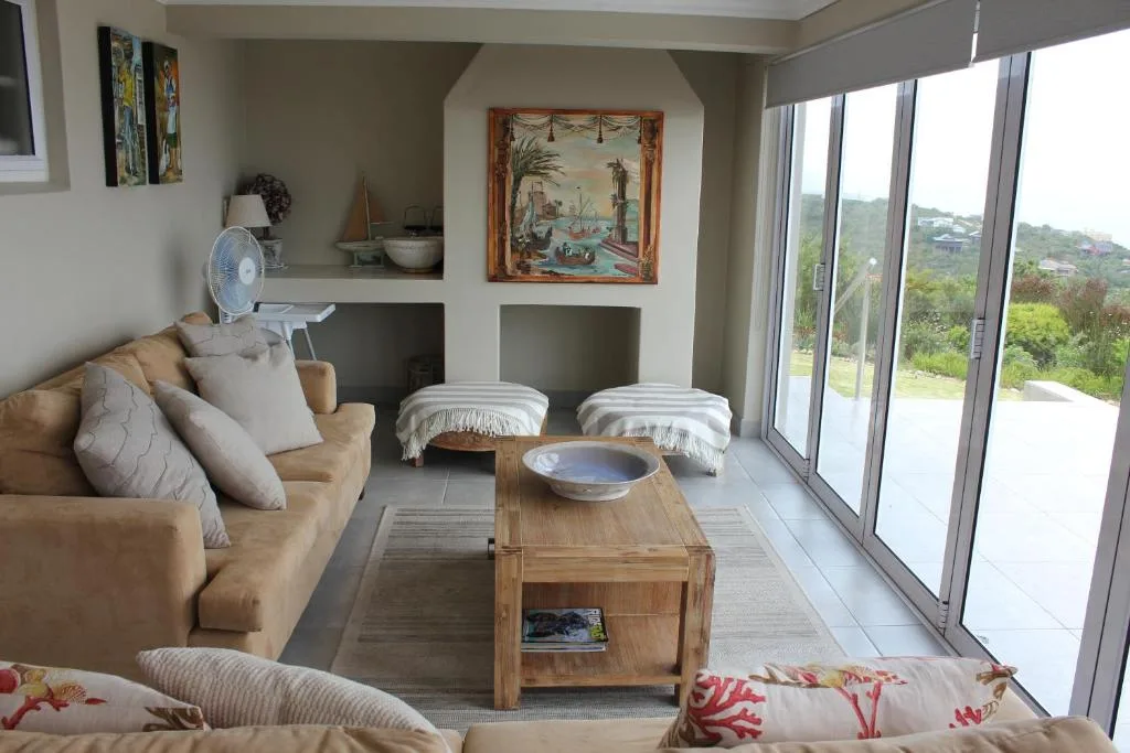 Spacious lounge with tan sofa, wooden coffee table, and scenic mountain views through glass doors